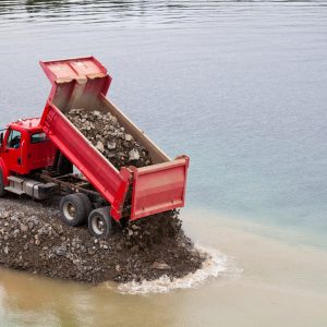 Red dump truck unloading earth fill